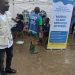 CADEF staff and partner personnel at a mobile-clinic tent with a banner describing available services in Limbe